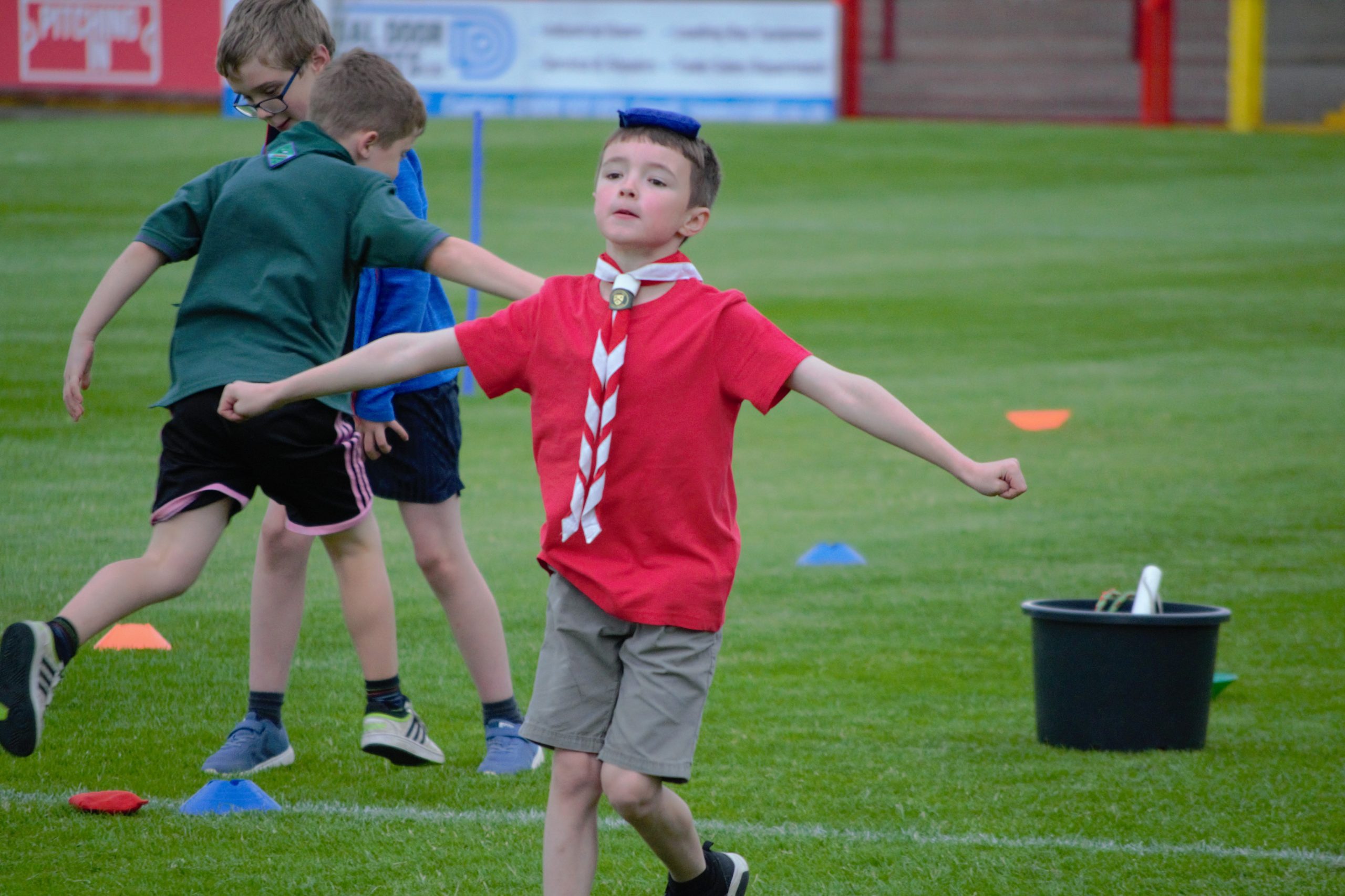 Cub Scout balancing beanbag on head. In background 2 Cub Scouts swap over beanbag