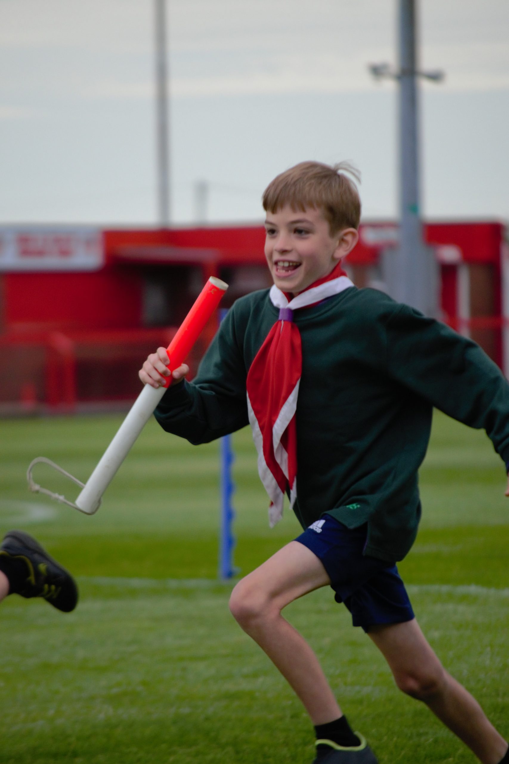 Cub Scout running with baton in relay