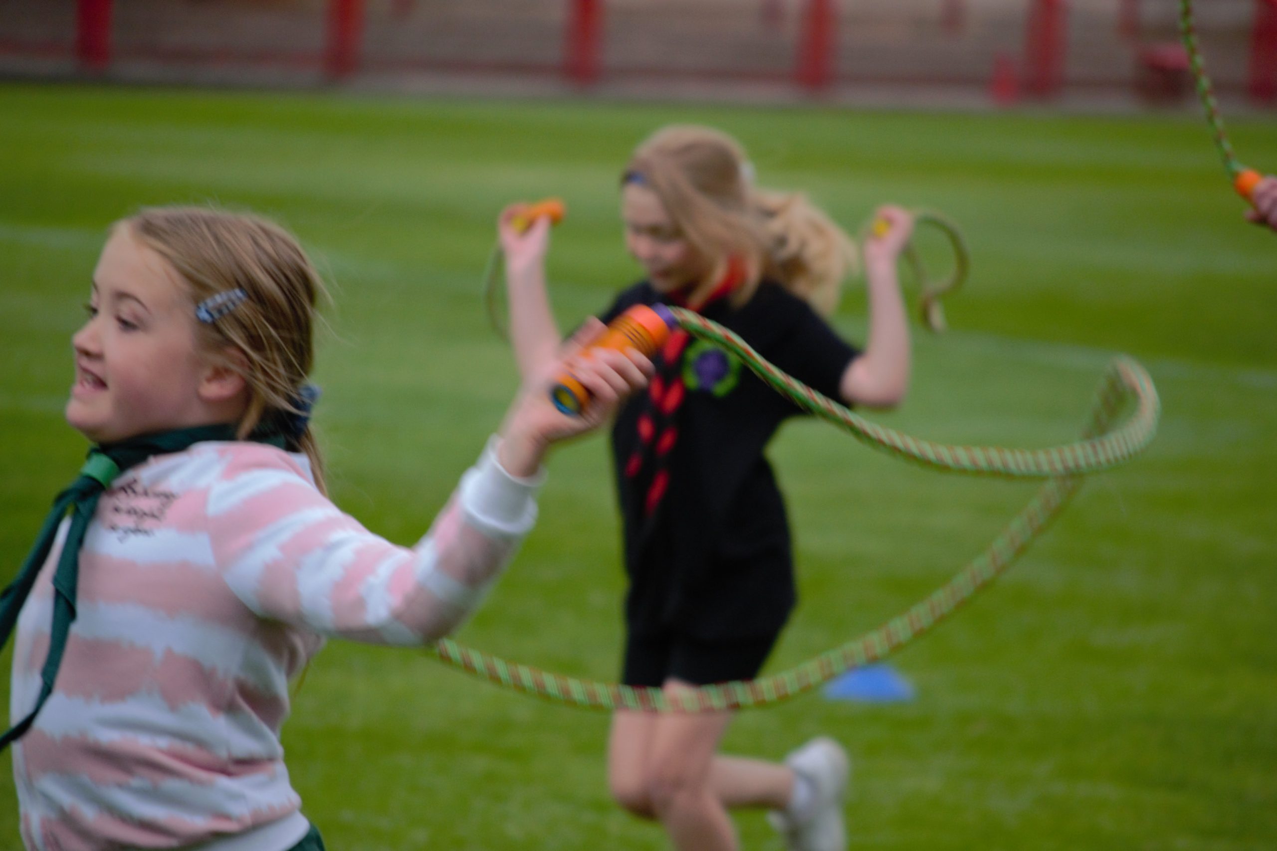 Cub Scout crossing finish line of skipping race as another Cub Scout skips on