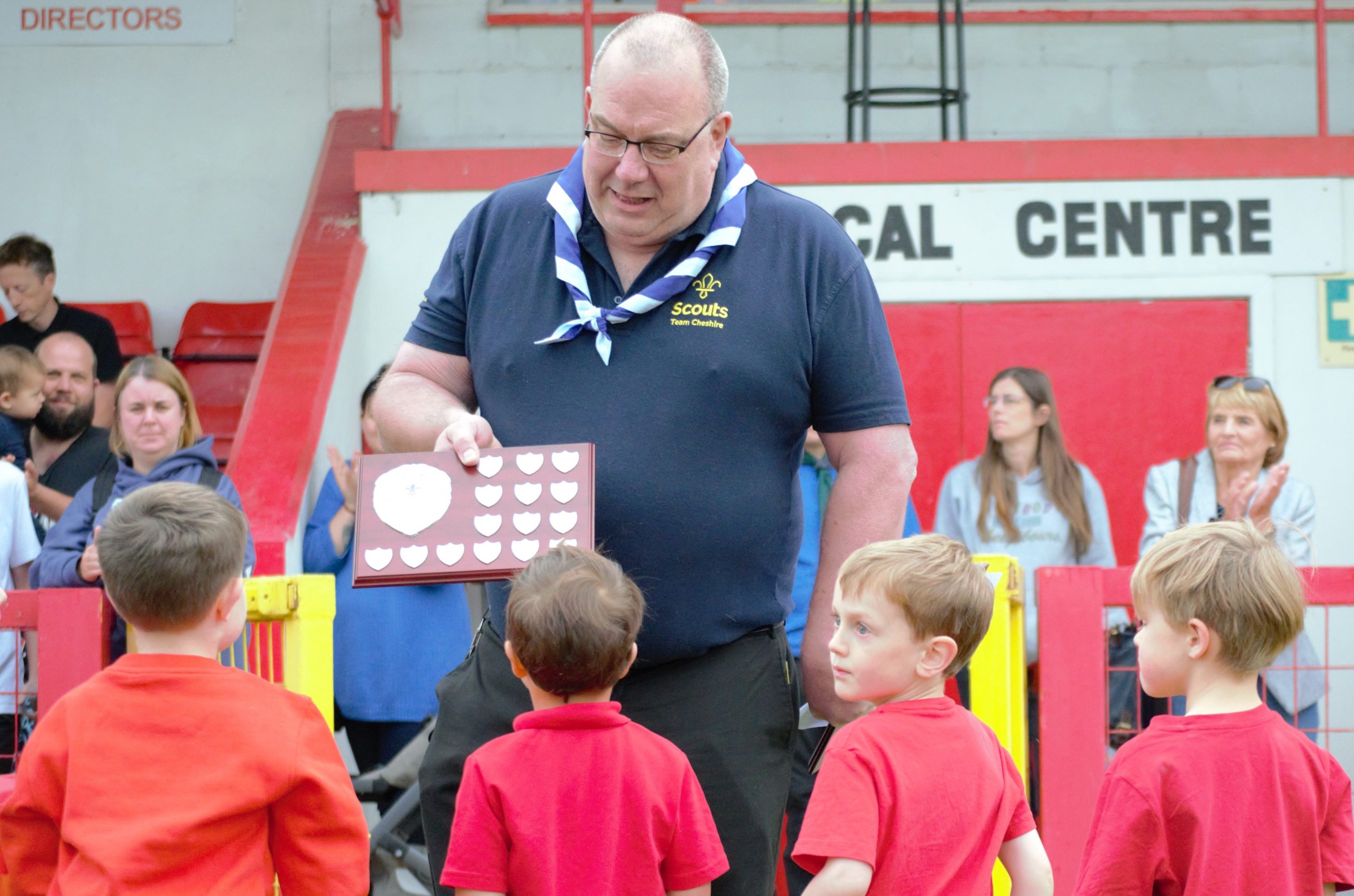 District Lead Volunteer awarding trophy to 4 Squirrel Scouts