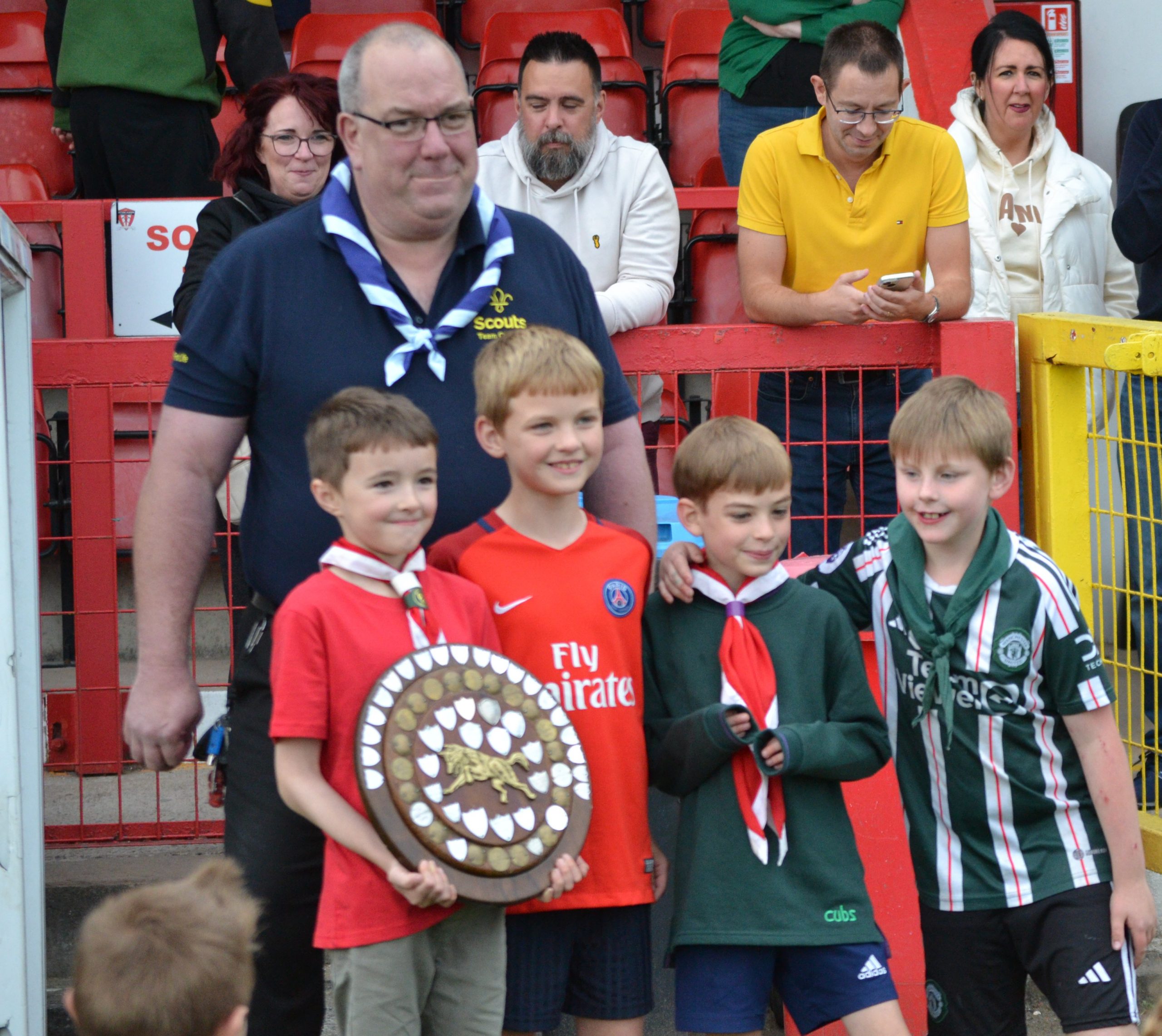 District Lead Volunteer with 4 Cub Scouts holding trophy